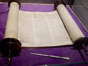 An open Torah scroll on its two rollers, in a museum case.