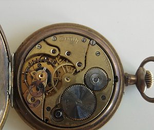 The open back of a pocket watch, showing the wheels and springs inside.