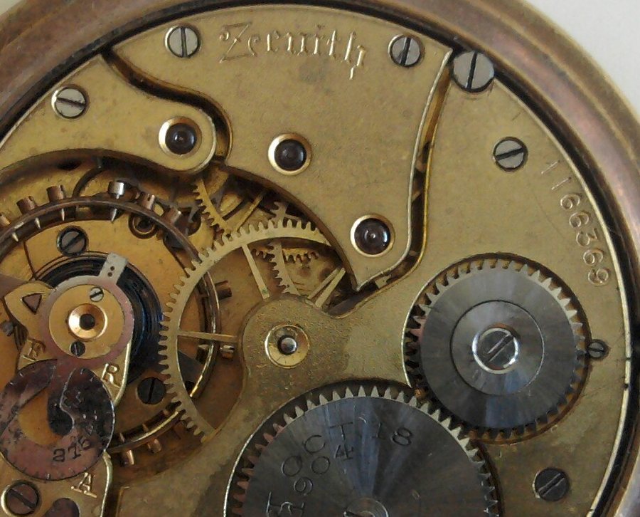 The open back of a pocket watch, showing the wheels and springs inside.